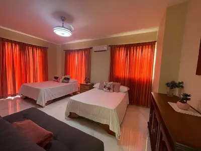 a living room with two beds and red curtains at Jeda Village in Higuey