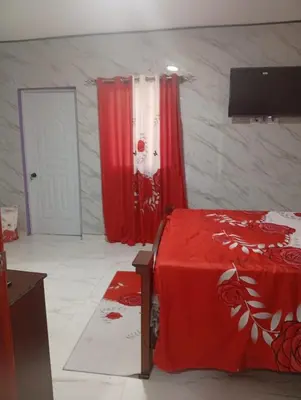 a room with a bed and red curtains and a door at Villa colombia in Miches