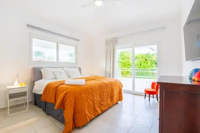 a bedroom with a bed with an orange blanket at Buganvilla 252 Cocotal Villa - 4BR, Private Pool, Jacuzzi, Golf View in Punta Cana