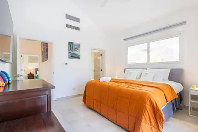 a bedroom with a large bed with an orange blanket at Buganvilla 252 Cocotal Villa - 4BR, Private Pool, Jacuzzi, Golf View in Punta Cana