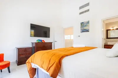 a bedroom with a bed and a tv on the wall at Buganvilla 252 Cocotal Villa - 4BR, Private Pool, Jacuzzi, Golf View in Punta Cana