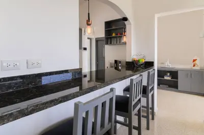 a kitchen with a bar with chairs and a counter at Casa Mango- Relax - Pool Stunning Views in San Felipe de Puerto Plata