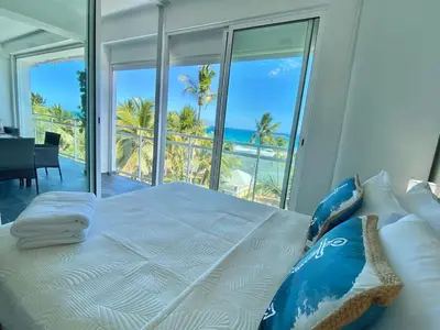 a bedroom with a bed with a view of the ocean at Cozy Beach Front Condo, Pool in La Puntica de Juan Dolio