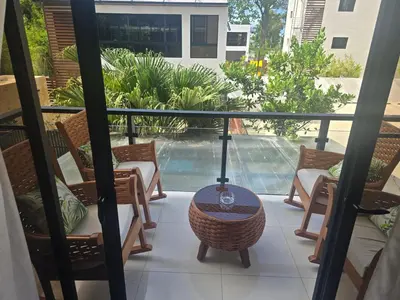 a balcony with chairs and a table and a pool at Sunset Apartment Beach Residences Steps from the Beach in Puerto Plata