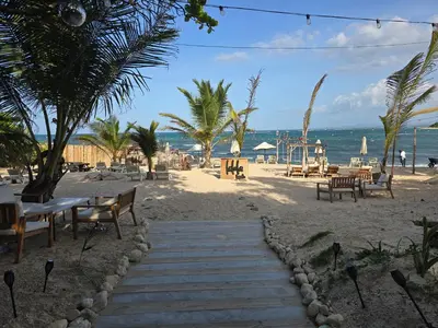 a sandy beach with tables and benches and the ocean at Sunset Apartment Beach Residences Steps from the Beach in Puerto Plata