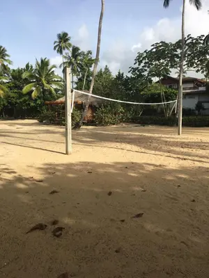 a volleyball net on a beach with palm trees at Apartment Balcones Del Atlantico in Las Terrenas