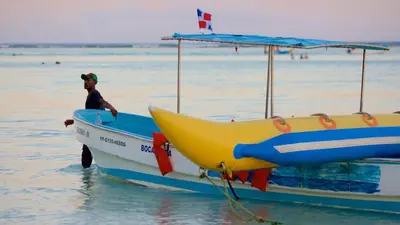 a man is standing on a boat in the water at Marvilla - Coastal Condo Poolside & Ocean View in Boca Chica