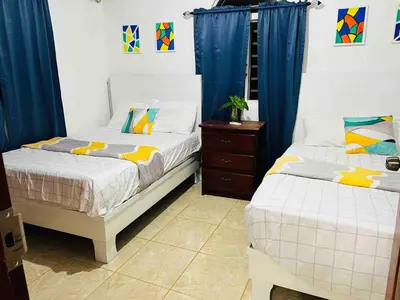 two beds in a bedroom with blue drapes at Cheerfull 4 bedroom Villa with pool #VillaLioness in Nagua
