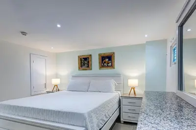 a bedroom with a white bed and two lamps at Apartamento Hermoso Frente Al Mar 11fl Amanzing in Juan Dolio