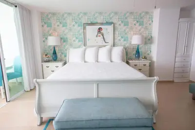 a bedroom with a large white bed with a blue stool at Luxury Penthhouse Frente Al Mar in Juan Dolio