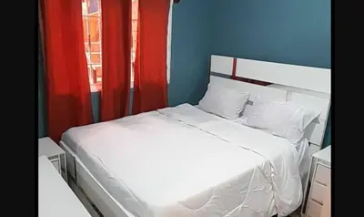 a bedroom with a white bed with red curtains at Don Carlos Recidencia