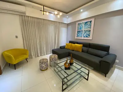 a living room with a black couch and a yellow chair at Maravilloso Descanso in Santo Domingo