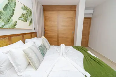 a bedroom with a bed with white sheets and pillows at Tropical 1BR Getaway in Dominicus Bayahibe - Garden Breeze
