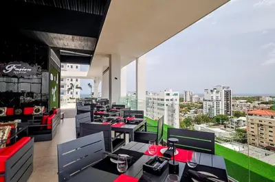 a restaurant with tables and chairs and a view of a city at Comfy Apt, Rooftop Lounge, Pool in Santo Domingo