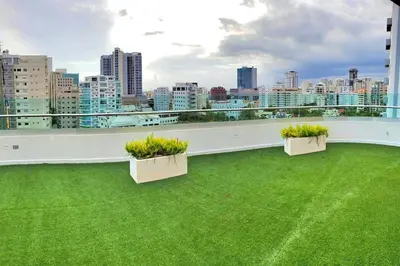 a balcony with green grass and two plants on it at Comfy 1BR Apt, Centric Full AC in Santo Domingo
