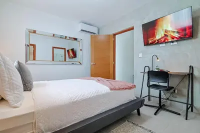 a bedroom with a bed and a desk and a mirror at Comfy 1BR Apt, Centric Full AC in Santo Domingo