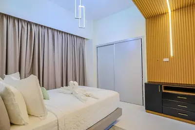 a bedroom with a bed with white sheets and a dresser at Luxury Upscale Centric Condo, in Santo Domingo