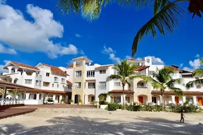 a large white building with palm trees in front at Loft short walk to the beach and restaurant in La Fragata