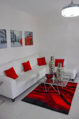 a white living room with a white couch and red pillows at Charming Apartment in Jarabacoa with Shared Pool in Jarabacoa