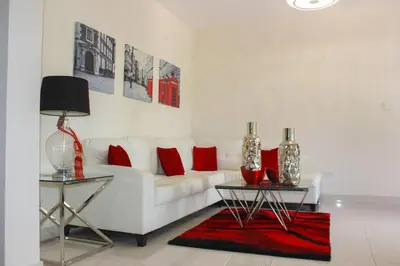 a living room with a white couch with red pillows at Charming Apartment in Jarabacoa with Shared Pool in Jarabacoa