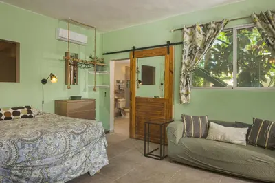 a bedroom with a bed and a couch and a window at Lux Garden Loft close to Beach, Kite-school in Cabarete
