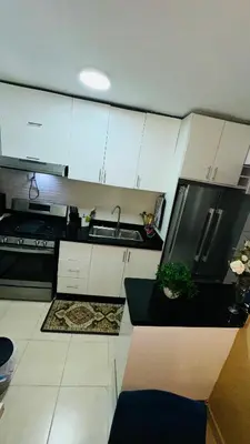 a kitchen with white cabinets and a black refrigerator at green oasis vacation retreat in La Grúa