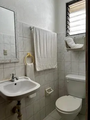 a white bathroom with a toilet and a sink at Dominico Colonial in Santo Domingo