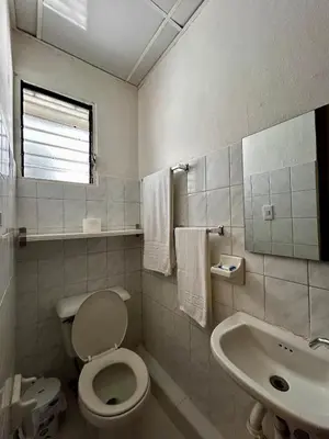 a white bathroom with a toilet and a sink at Dominico Colonial in Santo Domingo