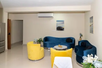 a living room with blue and yellow chairs and a table at La Isla Royal - Marea Estelar in Miches