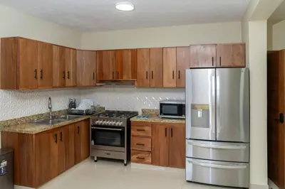 a kitchen with wooden cabinets and a stainless steel refrigerator at La Isla Royal - Marea Estelar in Miches