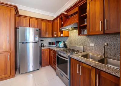 a kitchen with wooden cabinets and a stainless steel refrigerator at Stylish Punta Cana Apartment - Eden Caribe in Punta Cana
