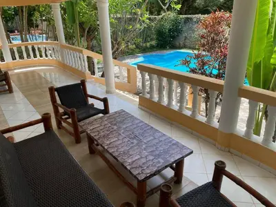 a porch with a table and chairs and a swimming pool at 4 bedroom villa, private pool, ocean view, security in Sosúa