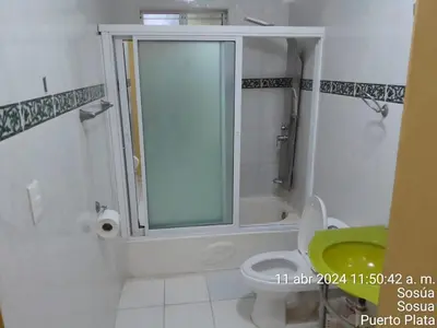 a bathroom with a shower and a toilet with a window at 4 bedroom villa, private pool, ocean view, security in Sosúa
