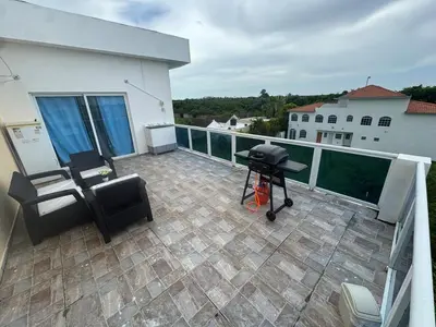 a patio with a grill and chairs on a balcony at Modern 3-Bedroom Apartment with Pool in Boca Chica