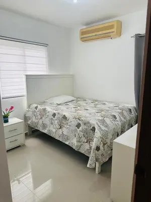a white bedroom with a bed and a window at Apartamento muy cerca de la embajada Americana in Santo Domingo