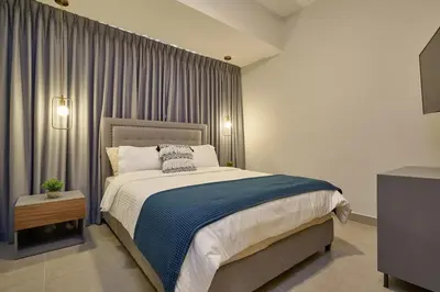 a bedroom with a large bed with a blue blanket at ®{PANO~VIEW~Experience} @DowntownSD PoolGym2BR in Santo Domingo
