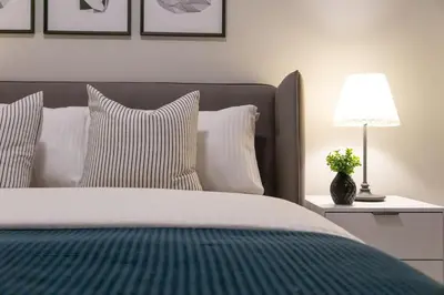 a bed with white pillows and a lamp on a table at ®{PANO~VIEW~Experience} @DowntownSD PoolGym2BR in Santo Domingo