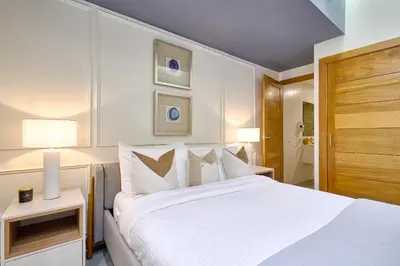 a white bedroom with a large bed and two lamps at ®{Designer~City~Stay} @DowntownSD NearPark1BR in Santo Domingo