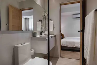 a bathroom with a toilet and a mirror and a bed at ®{LUX~City~Skyline} @DowntownSD PrivéJaccuziGym in Santo Domingo
