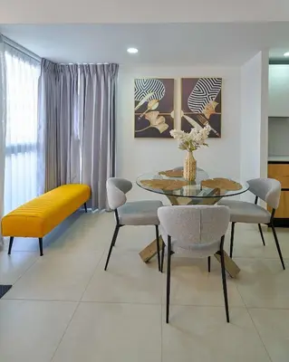 a dining room with a table and chairs and a yellow bench at ®2BR{The~City~Center}@DTown PoolGym NearCecilip in Santo Domingo