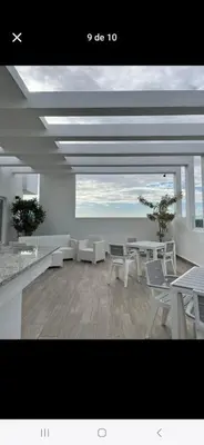 a room with white tables and chairs and the ocean at Colinas del arroyo in Santo Domingo