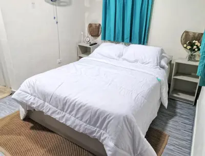 a bedroom with a large white bed with blue curtains at Habitacion cerca de la Playa in Boca Chica
