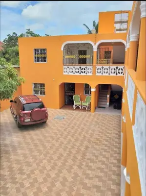 a house with a car parked in front of it at Apartamentos España in Sosúa
