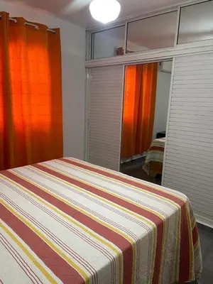 a bedroom with a bed with a striped blanket on it at Apartamentos España in Sosúa