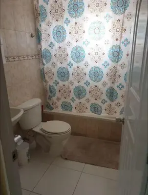 a bathroom with a toilet and a shower curtain at Apartamentos España in Sosúa