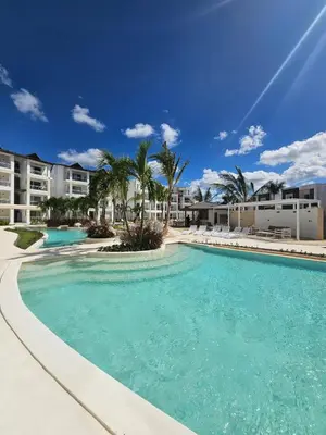 a large swimming pool with palm trees and condos at Garden Breeze Penthouse & Pool View l Ghibli 401 in La Laguna