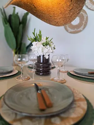a table with a plate and wine glasses and flowers at Garden Breeze Penthouse & Pool View l Mistral 401 in La Laguna