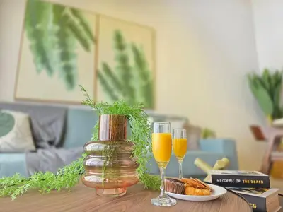 two glasses of orange juice and a vase on a table at Garden Breeze Penthouse & Pool View l Mistral 401 in La Laguna