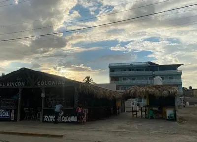 a building with a straw roof next to a building at Apartamento de recreación vista al mar in Boca Chica