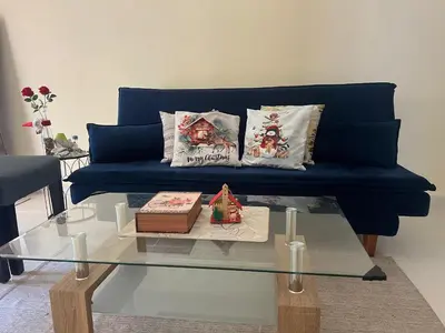 a blue couch with two pillows and a cake on a glass table at Olas del caribe DR in Santo Domingo
